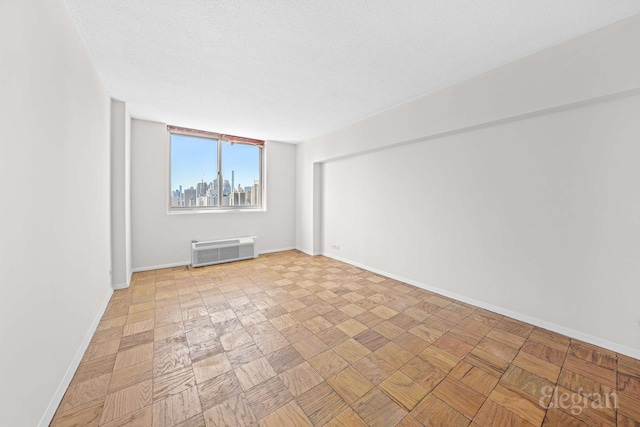 spare room featuring a textured ceiling, baseboards, and a wall mounted air conditioner