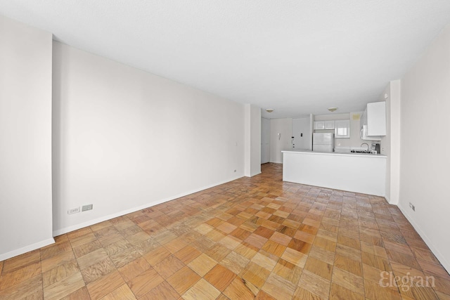 unfurnished living room with a sink and baseboards