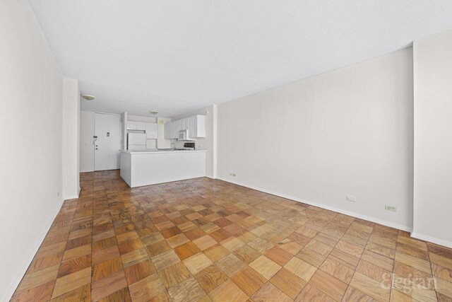unfurnished living room with baseboards