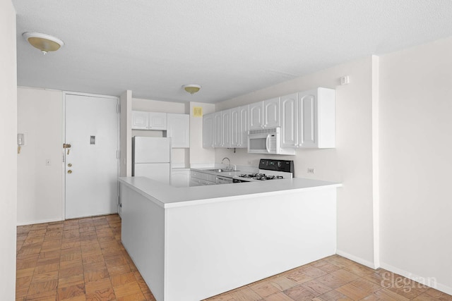 kitchen featuring a sink, light countertops, white cabinets, and white appliances