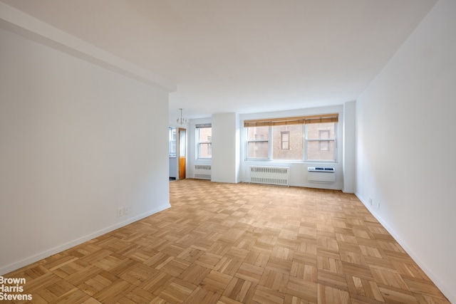 unfurnished living room with baseboards, a wall unit AC, and radiator heating unit