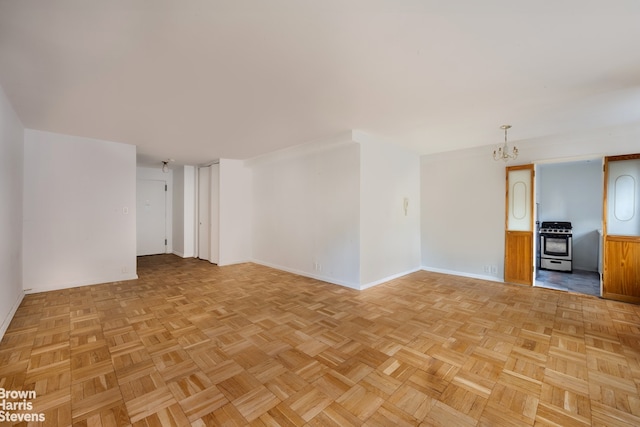 spare room featuring baseboards and an inviting chandelier