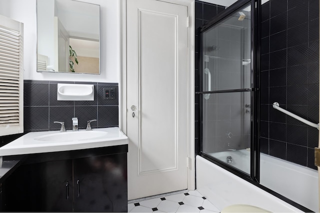 1165 Park Ave Unit 10A, New York City, NY 10128 - bathroom featuring bath / shower combo with glass door, tile walls, vanity, and a wainscoted wall