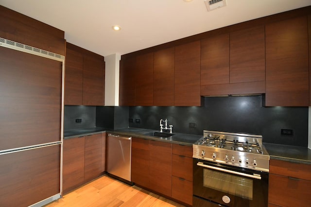 kitchen with visible vents, dark countertops, tasteful backsplash, a sink, and stainless steel appliances