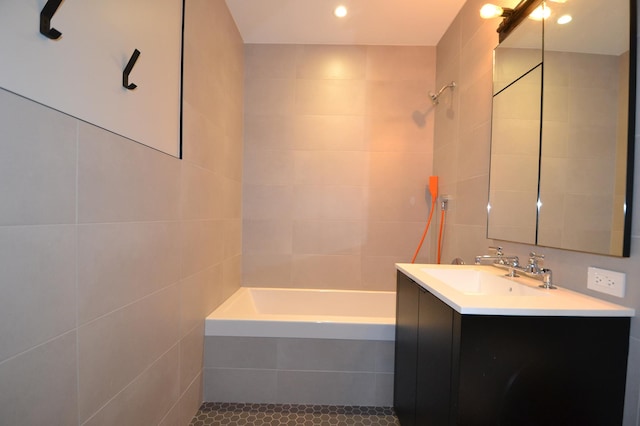 bathroom featuring tiled shower / bath, tile patterned floors, tile walls, and vanity