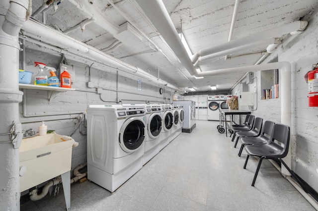 shared laundry area with washing machine and clothes dryer, a sink, and light floors