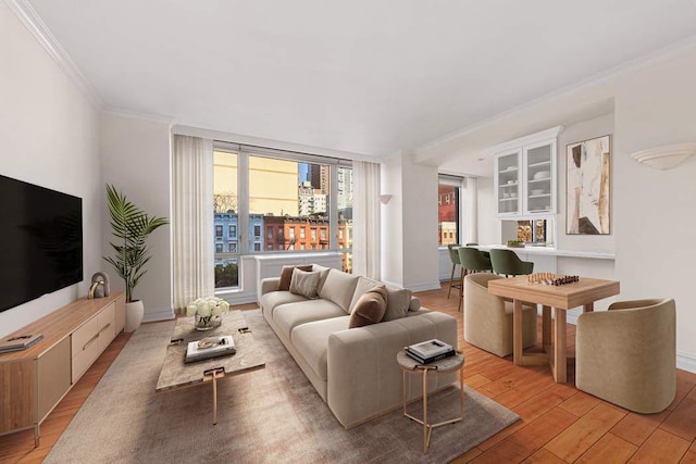 living area with light wood-type flooring, ornamental molding, and baseboards