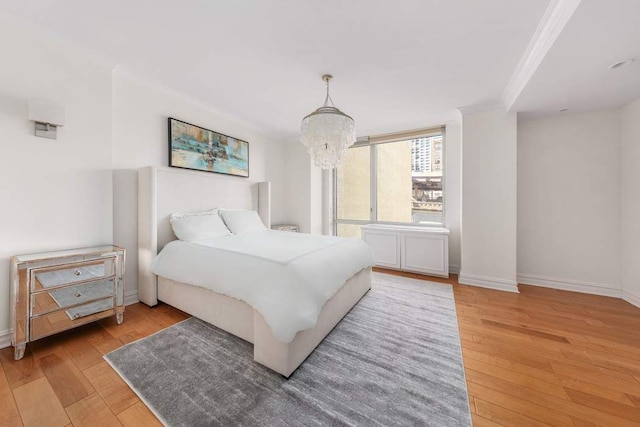 bedroom featuring an inviting chandelier, ornamental molding, light wood-style flooring, and baseboards