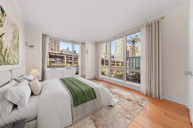 bedroom with crown molding, a city view, baseboards, and wood finished floors