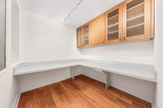 unfurnished office with baseboards, rail lighting, and hardwood / wood-style floors
