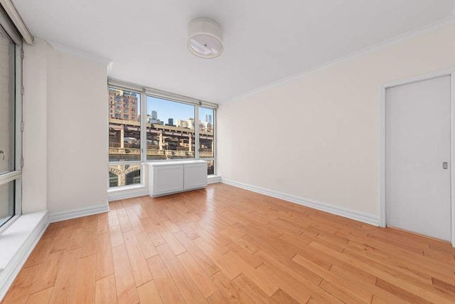 401 E 60th St Unit 4C, New York City, NY 10065 - unfurnished room featuring a city view, light wood-type flooring, crown molding, floor to ceiling windows, and baseboards