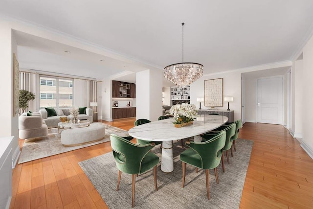 dining area with an inviting chandelier, baseboards, ornamental molding, and hardwood / wood-style flooring