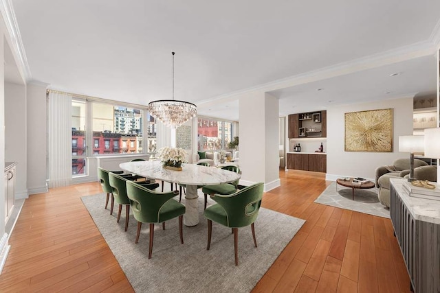 dining room featuring baseboards, a chandelier, ornamental molding, and light wood-style floors