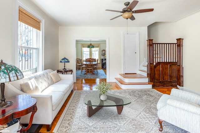 living area with ceiling fan, wood finished floors, and stairway