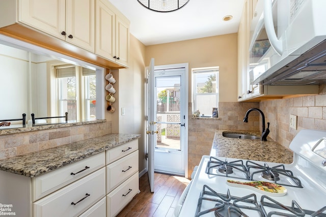 kitchen with white appliances, a wealth of natural light, a sink, and light wood finished floors
