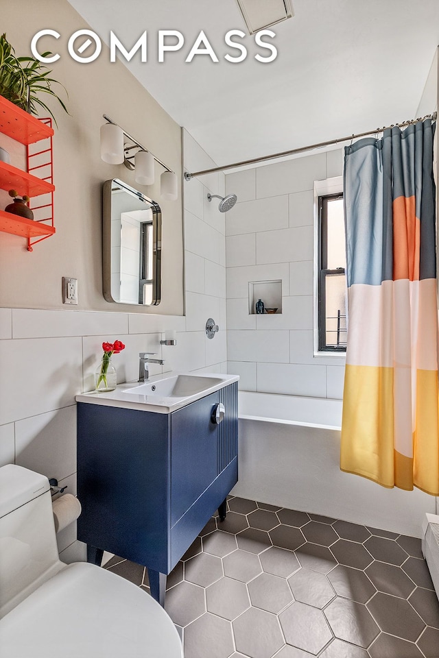 bathroom with toilet, tile walls, tile patterned flooring, and vanity