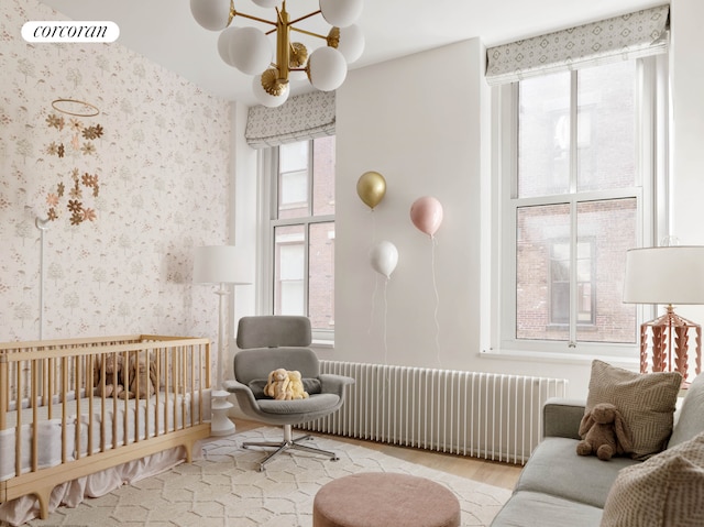 63 Greene St Unit Loft4D, New York City, NY 10012 - bedroom with radiator heating unit, a chandelier, a nursery area, wallpapered walls, and wood finished floors