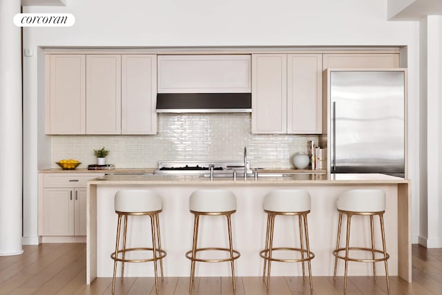 63 Greene St Unit Loft4D, New York City, NY 10012 - kitchen featuring range hood, stainless steel built in fridge, decorative backsplash, and a breakfast bar area