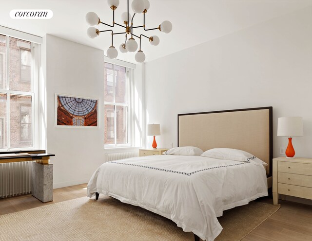 63 Greene St Unit Loft4D, New York City, NY 10012 - bedroom featuring wood finished floors, a chandelier, and radiator