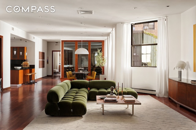 living area with visible vents, a baseboard heating unit, and dark wood-style floors