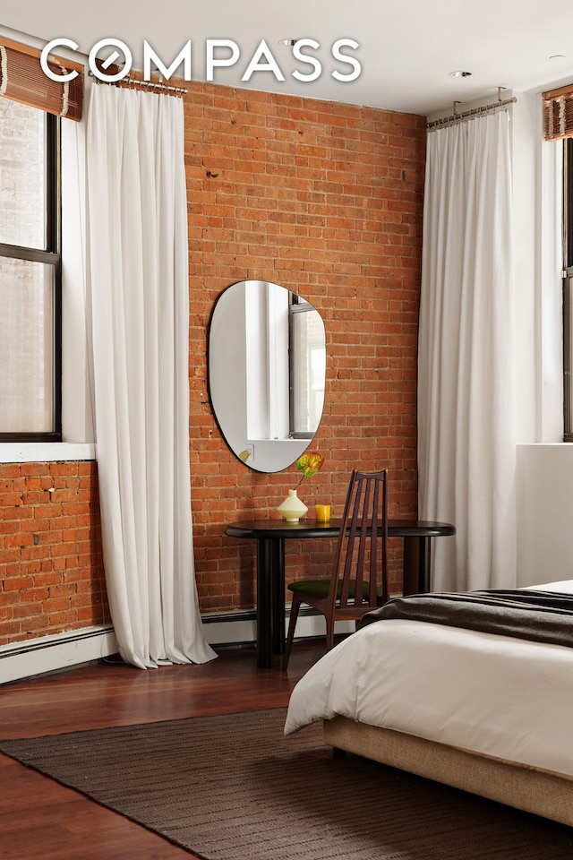 bedroom featuring baseboards, brick wall, and wood finished floors