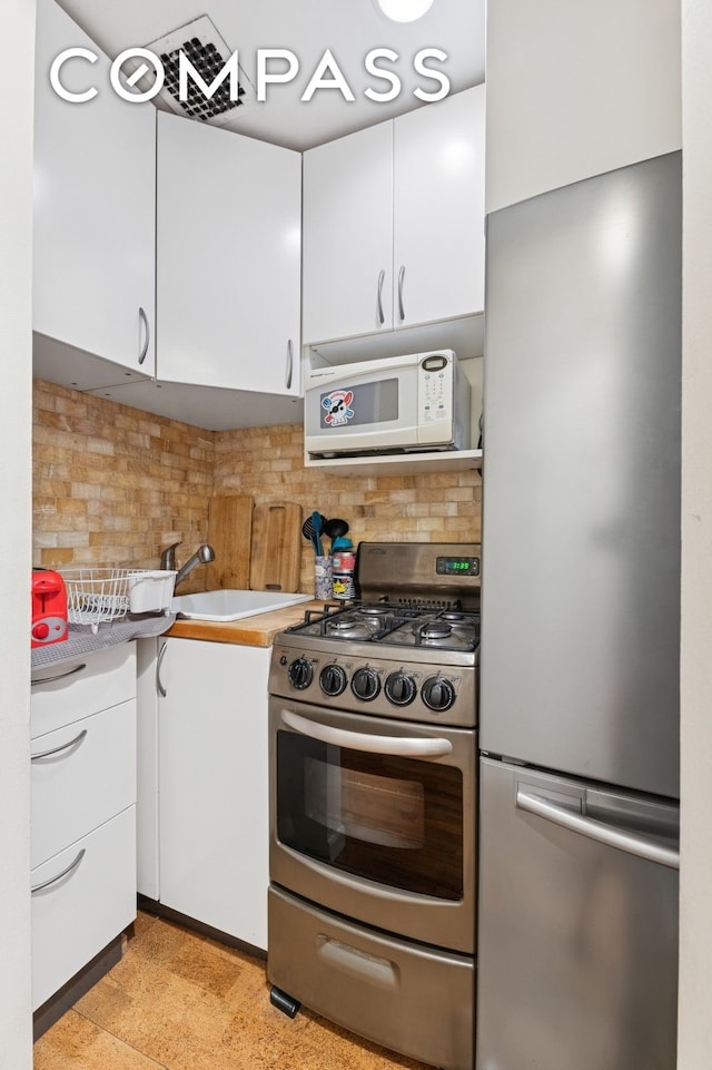kitchen featuring white cabinetry, appliances with stainless steel finishes, and tasteful backsplash