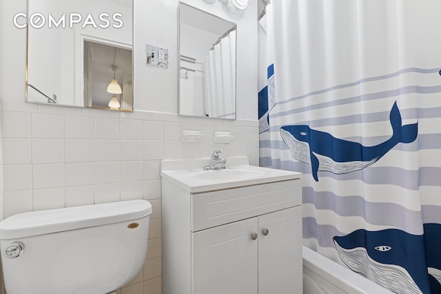 bathroom featuring vanity, toilet, and tile walls