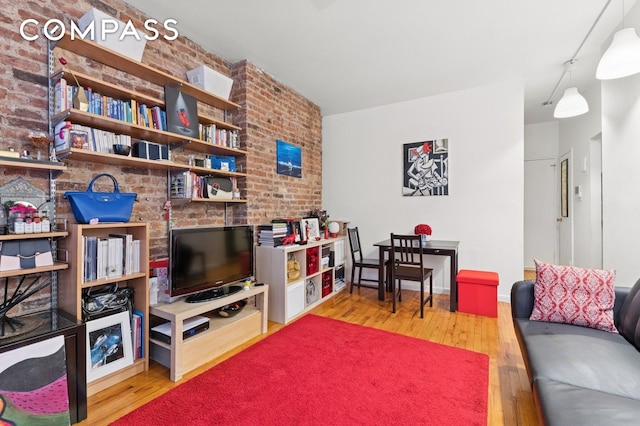living room featuring wood-type flooring and brick wall