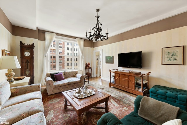 living area with baseboards, an inviting chandelier, and wood finished floors