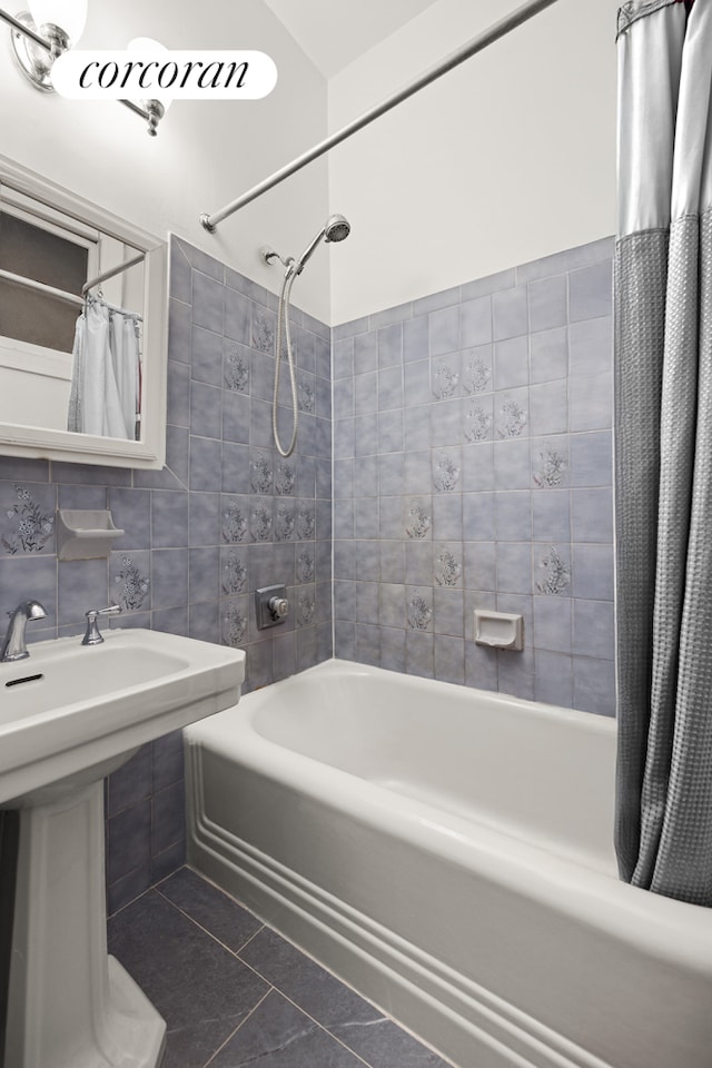 full bathroom featuring a sink, tile walls, shower / bath combo with shower curtain, and tile patterned floors
