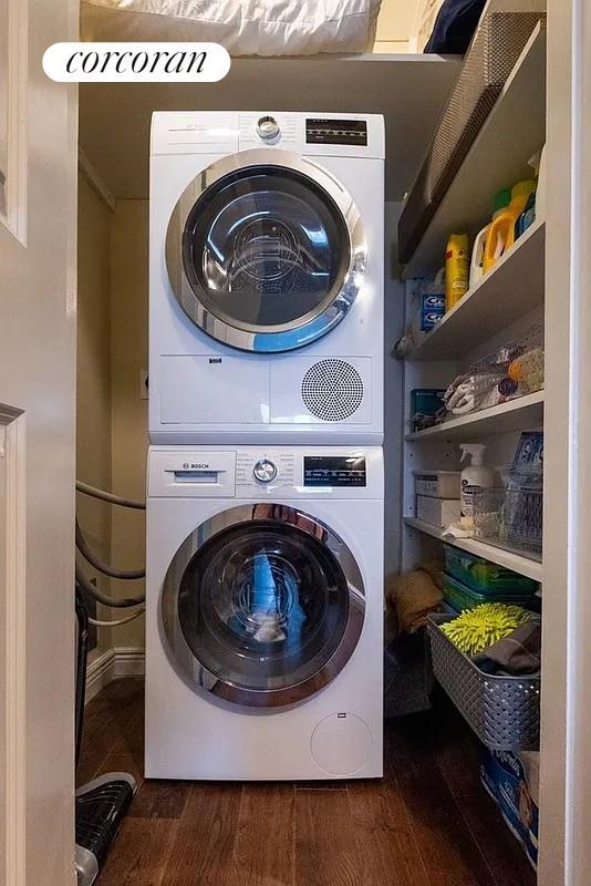 303 E 57th St Unit 16F, New York City, NY 10022 - laundry room with stacked washer and clothes dryer and dark wood finished floors