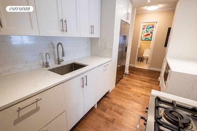 303 E 57th St Unit 16F, New York City, NY 10022 - kitchen with a sink, white cabinets, light wood-style floors, tasteful backsplash, and gas range oven