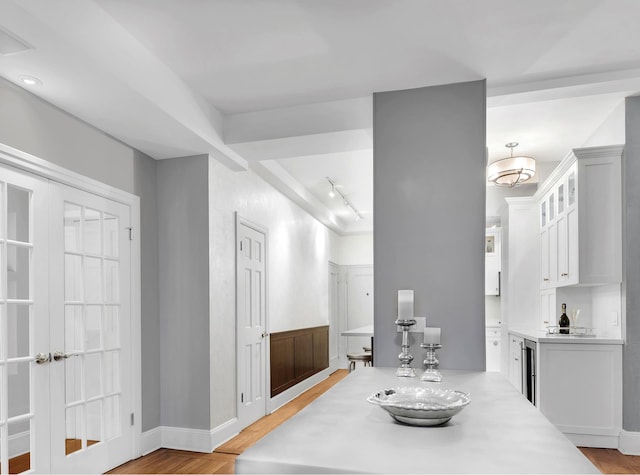 dining space with light wood-style floors, rail lighting, baseboards, and indoor wet bar