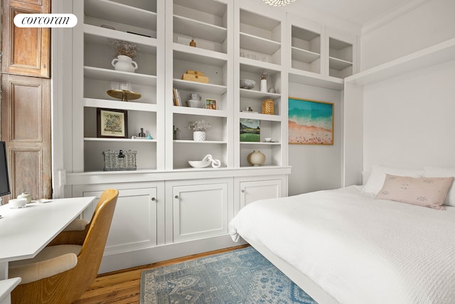 bedroom with ornamental molding and wood finished floors