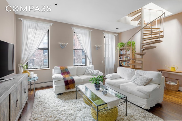 living room featuring a baseboard heating unit, stairs, and wood finished floors