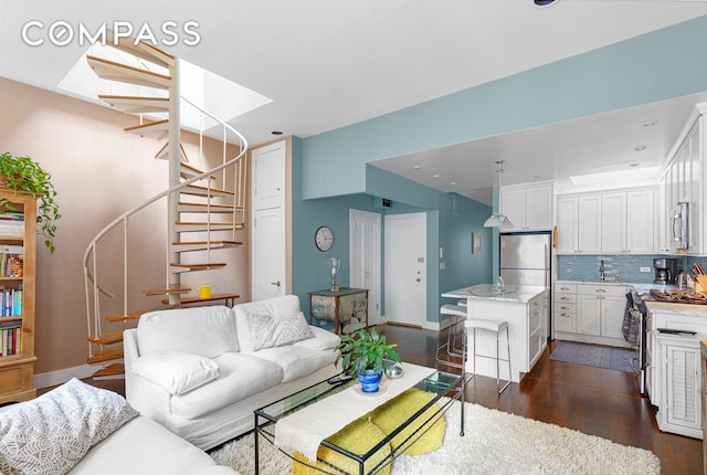 living area with a skylight, baseboards, stairs, and dark wood finished floors