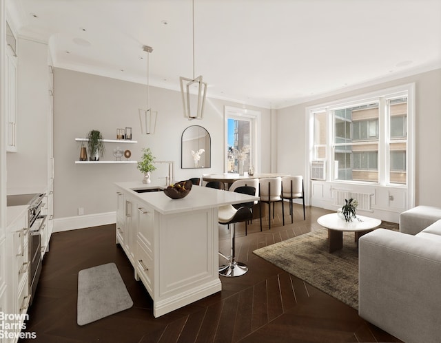 kitchen with white cabinets, a sink, a kitchen island with sink, a kitchen breakfast bar, and high end stainless steel range oven