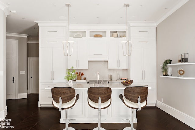 kitchen featuring crown molding, baseboards, light countertops, white cabinetry, and a sink
