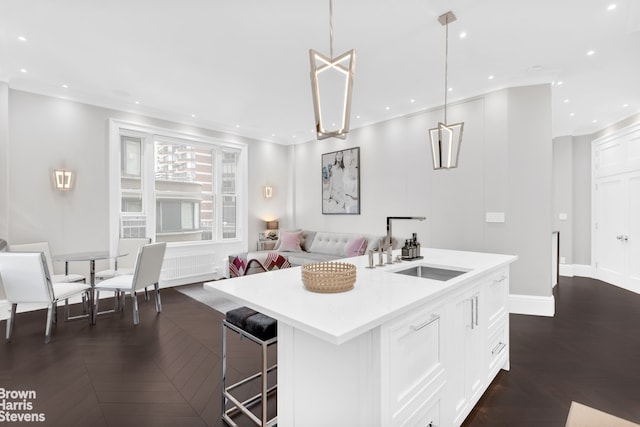 kitchen featuring a kitchen island with sink, open floor plan, light countertops, white cabinets, and a sink