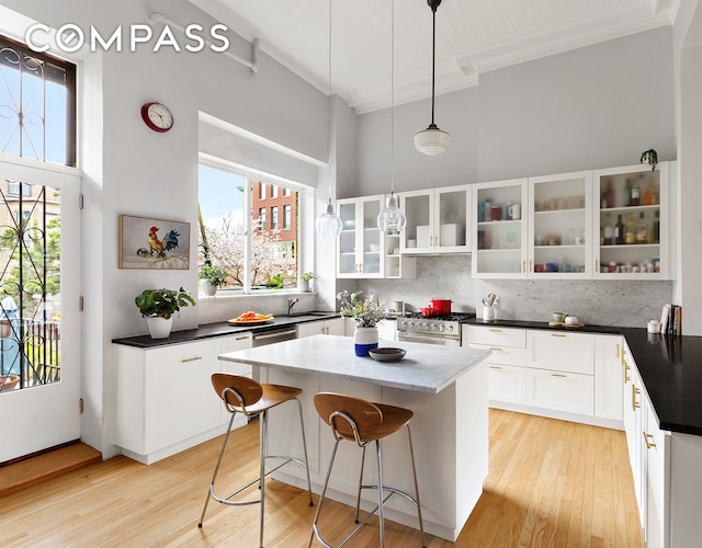 kitchen with decorative backsplash, crown molding, appliances with stainless steel finishes, a center island, and a sink