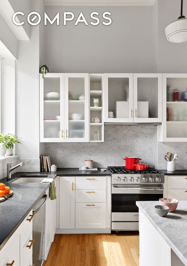 kitchen with a sink, light wood-style flooring, white cabinets, and gas range