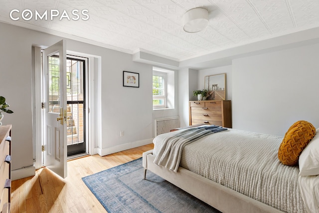 bedroom featuring access to exterior, wood finished floors, baseboards, an ornate ceiling, and ornamental molding