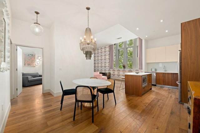 dining space with recessed lighting, baseboards, light wood finished floors, and a notable chandelier