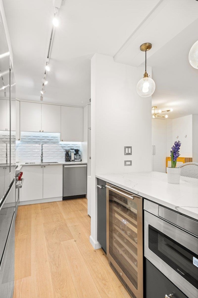 kitchen featuring track lighting, wine cooler, white cabinetry, light wood-style flooring, and stainless steel appliances