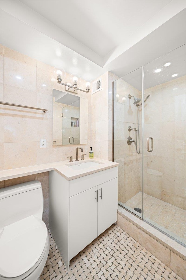full bath featuring visible vents, tile walls, a stall shower, vanity, and toilet