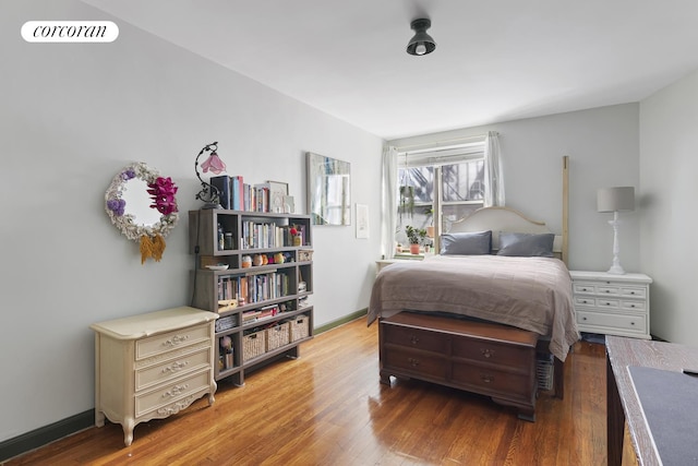 bedroom with baseboards, visible vents, and wood finished floors