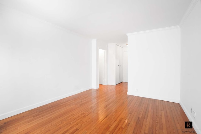 unfurnished room with crown molding, light wood-style flooring, and baseboards