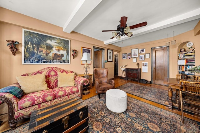 living area featuring beamed ceiling, a ceiling fan, and wood finished floors