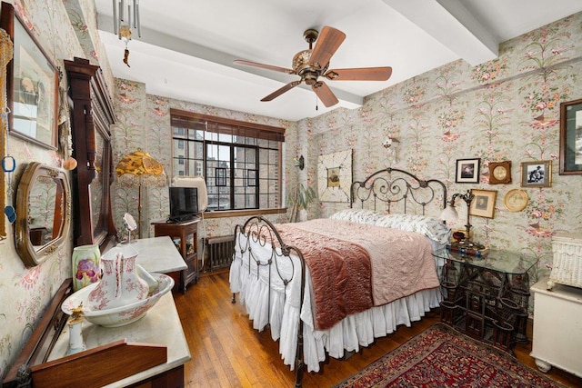 bedroom with wood-type flooring, beamed ceiling, radiator heating unit, and wallpapered walls