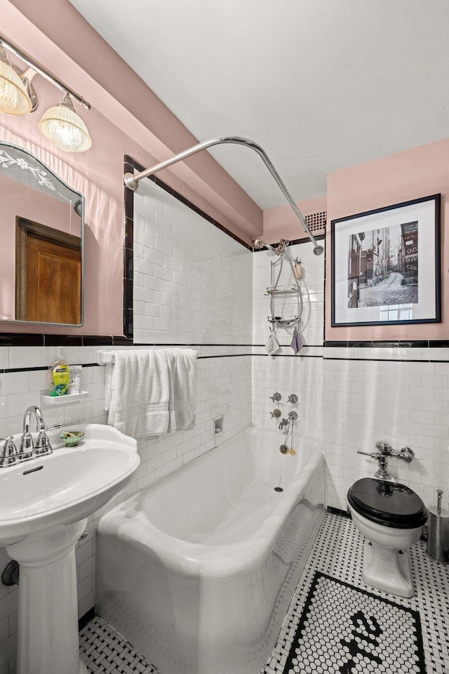 bathroom with wainscoting, tile patterned floors, toilet, and tile walls